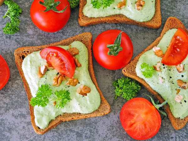 Toast with green cottage cheese, nuts and tomatoes. Rye toast. The concept of a useful snack.