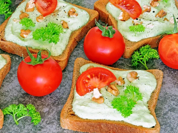 Toast with green cottage cheese, nuts and tomatoes. Rye toast. The concept of a useful snack.