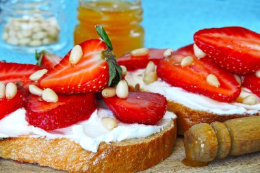 Çilek, bal ve çam fıstığı ile beyaz krem peynir ile kızarmış ekmek.
