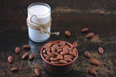 Badem sütü ve şık eski püskü arka plan üzerinde bir kapta çiğ badem. Badem sütü pişirme özgünlük kavramı. Vegan süt.