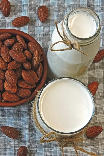 Almond milk in a glass and bottle. Fresh raw almonds. Nut milk.