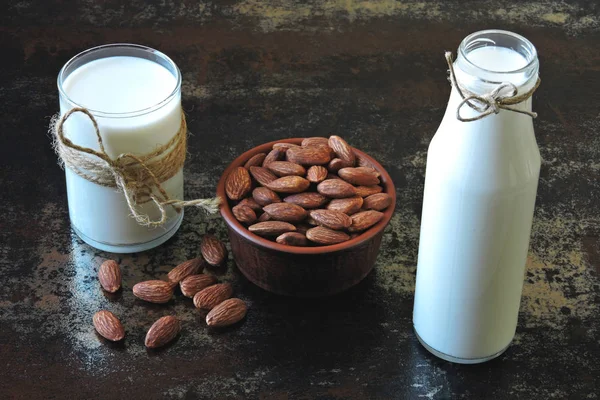 Almond milk and raw almonds in a bowl on a stylish shabby background. The concept of authenticity of cooking almond milk. Vegan milk.