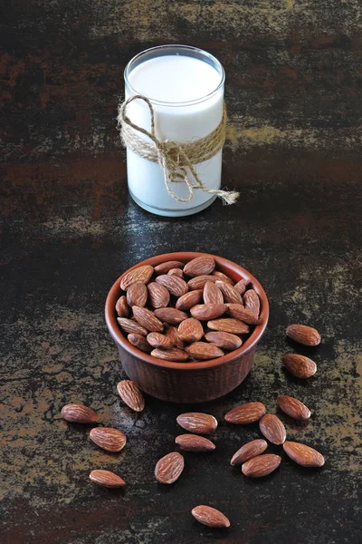 Almond milk and raw almonds in a bowl on a stylish shabby background. The concept of authenticity of cooking almond milk. Vegan milk.