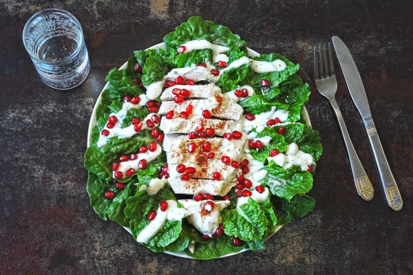 Healthy green salad with romaine lettuce, turkey breast, pomegranate and yoghurt sauce. Superfoods. Healthy eating concept. Keto lunch idea. Christmas salad with pomegranate and turkey.
