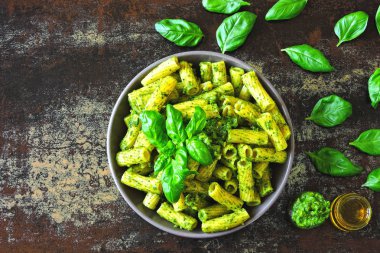 Pesto ve fesleğen ile iştah açıcı makarna. Pesto makarna ile vegan kase. Pesto soslu makarna çeşitleri. Taze fesleğen yaprağı.