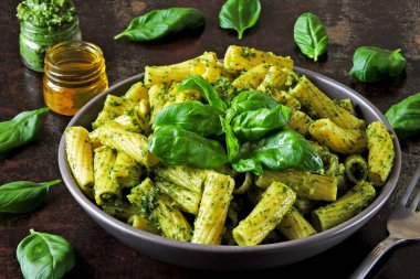 Pesto ve fesleğen ile iştah açıcı makarna. Pesto makarna ile vegan kase. Pesto soslu makarna çeşitleri. Taze fesleğen yaprağı.