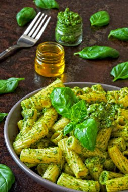 Pesto ve fesleğen ile iştah açıcı makarna. Pesto makarna ile vegan kase. Pesto soslu makarna çeşitleri. Taze fesleğen yaprağı.