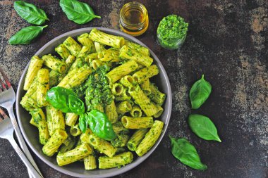 Pesto ve fesleğen ile iştah açıcı makarna. Pesto makarna ile vegan kase. Pesto soslu makarna çeşitleri. Taze fesleğen yaprağı.