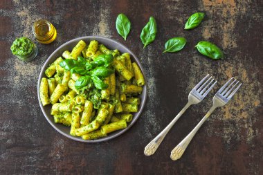 Pesto ve fesleğen ile iştah açıcı makarna. Pesto makarna ile vegan kase. Pesto soslu makarna çeşitleri. Taze fesleğen yaprağı.