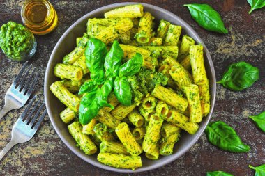 Pesto ve fesleğen ile iştah açıcı makarna. Pesto makarna ile vegan kase. Pesto soslu makarna çeşitleri. Taze fesleğen yaprağı.