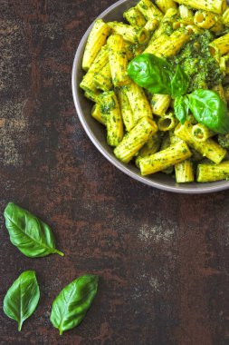Pesto ve fesleğen ile iştah açıcı makarna. Pesto makarna ile vegan kase. Pesto soslu makarna çeşitleri. Taze fesleğen yaprağı.