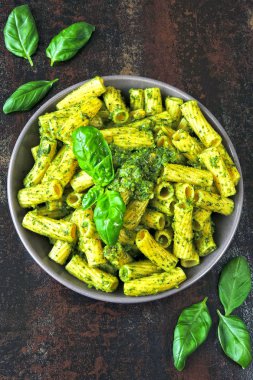 Pesto ve fesleğen ile iştah açıcı makarna. Pesto makarna ile vegan kase. Pesto soslu makarna çeşitleri. Taze fesleğen yaprağı.