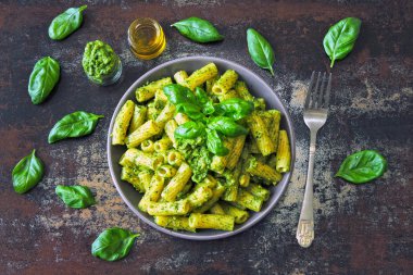 Pesto ve fesleğen ile iştah açıcı makarna. Pesto makarna ile vegan kase. Pesto soslu makarna çeşitleri. Taze fesleğen yaprağı.