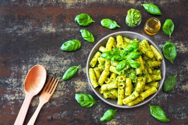Pesto ve fesleğen ile iştah açıcı makarna. Pesto makarna ile vegan kase. Pesto soslu makarna çeşitleri. Taze fesleğen yaprağı.
