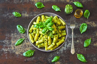 Pesto ve fesleğen ile iştah açıcı makarna. Pesto makarna ile vegan kase. Pesto soslu makarna çeşitleri. Taze fesleğen yaprağı.