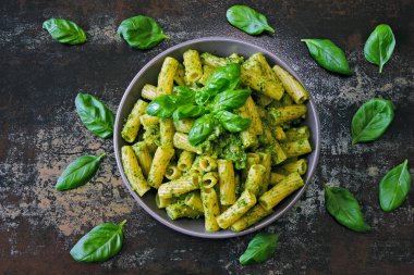 Pesto ve fesleğen ile iştah açıcı makarna. Pesto makarna ile vegan kase. Pesto soslu makarna çeşitleri. Taze fesleğen yaprağı.