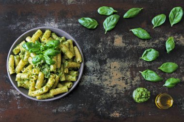 Pesto ve fesleğen ile iştah açıcı makarna. Pesto makarna ile vegan kase. Pesto soslu makarna çeşitleri. Taze fesleğen yaprağı.
