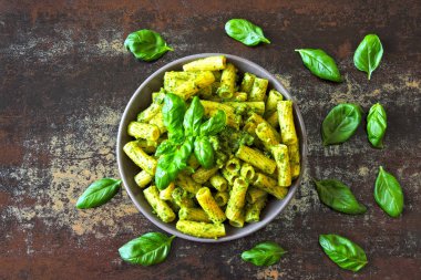 Pesto ve fesleğen ile iştah açıcı makarna. Pesto makarna ile vegan kase. Pesto soslu makarna çeşitleri. Taze fesleğen yaprağı.