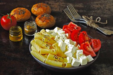 Makarna domates ve beyaz peynir ile. Makarna, domates ve beyaz bir vejetaryen kase. Zeytin yağı ile buns. Sağlıklı İtalyan tarzı yemek.