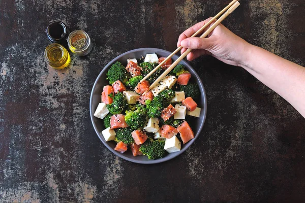 Poke bowl with salmon. Salmon broccoli sesame poke. Top view. Food sticks.