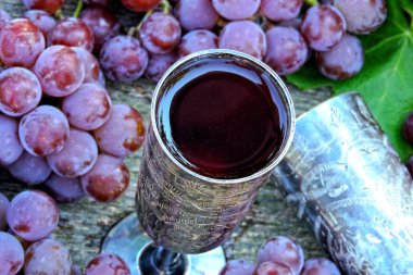 Üzüm gümüş bardaklarda şarap. Üzüm ve üzüm yaprakları. Pembe üzüm hasat. Natürmort şarap ve üzüm.