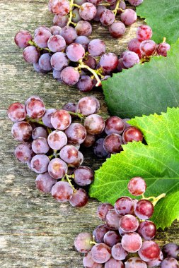 Demet pembe üzüm ve üzüm yaprakları bir ahşap yüzeyde. Üzüm hasat.