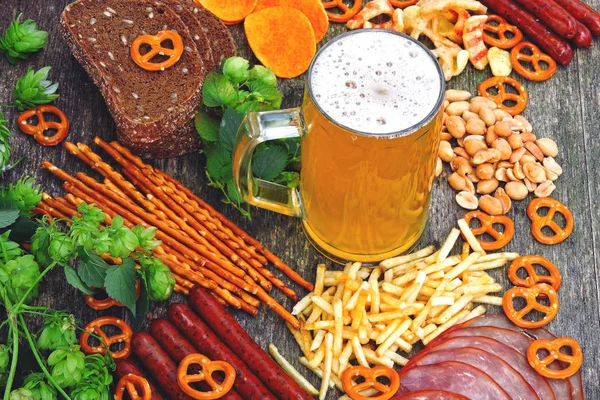 Oktoberfest food menu. Sausages, beer snacks, pretzels, a glass of beer on a wooden background. Oktoberfest mood.