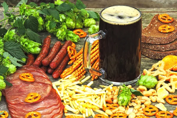 Oktoberfest food menu. Sausages, beer snacks, pretzels, a glass of dark beer on a wooden background.