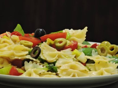 Makarna bir plaka üzerinde zeytin, fesleğen ve kiraz domates ile yay.