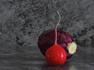 Parlak kırmızı turp ve mavi lahana. Gri arka plan çizilmeye. Yazma alanı.