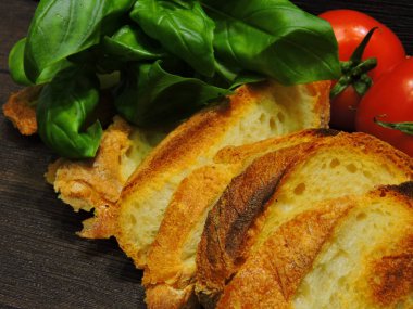 İtalyan bruschetta tarifi. Üçüncü adım. Baget ekmeğinden tost. Kuyruklu domatesler. Parlak yeşil fesleğen. Sarımsaklı karanfil..