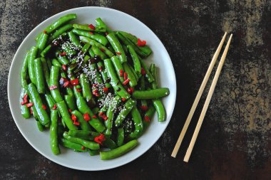 Kırmızı biberli ve susamlı bezelye kabukları. Çin tarzında yeşil kapsüller..