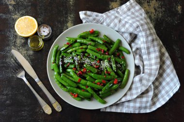 Kırmızı biberli ve susamlı bezelye kabukları. Çin tarzında yeşil kapsüller..