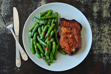 Keto öğle yemeği ya da akşam yemeği. Tabakta biftekli yeşil bezelye. Kırmızı biber ve soya soslu yeşil bezelye kabukları. Biftek. Dengeli bir diyete bir örnek. Keto diyeti. Paleo diyeti. Pegan diyeti.