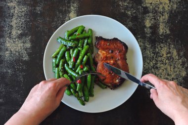 Keto öğle yemeği ya da akşam yemeği. Tabakta biftekli yeşil bezelye. Kırmızı biber ve soya soslu yeşil bezelye kabukları. Biftek. Dengeli bir diyete bir örnek. Keto diyeti. Paleo diyeti. Pegan diyeti.