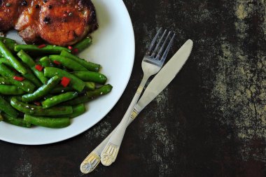 Keto öğle yemeği ya da akşam yemeği. Tabakta biftekli yeşil bezelye. Kırmızı biber ve soya soslu yeşil bezelye kabukları. Biftek. Dengeli bir diyete bir örnek. Keto diyeti. Paleo diyeti. Pegan diyeti.