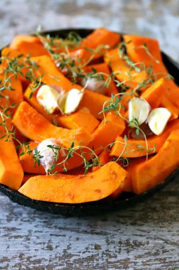 Pişirmeden önce kekik ve sarımsaklı bir tavada dilimlenmiş balkabağı. Balkabağı pişiriyorum..