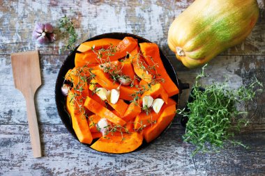 Pişirmeden önce kekik ve sarımsaklı bir tavada dilimlenmiş balkabağı. Balkabağı pişiriyorum..