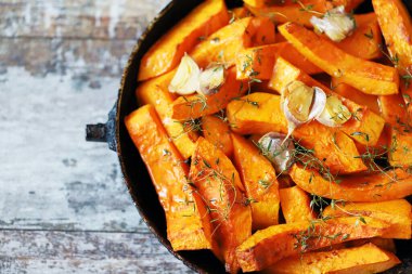 Pişirmeden önce kekik ve sarımsaklı bir tavada dilimlenmiş balkabağı. Balkabağı pişiriyorum..