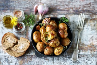 Tavadaki kırsal patates. Sarımsak ve bitkilerle kabuklu küçük patatesler..