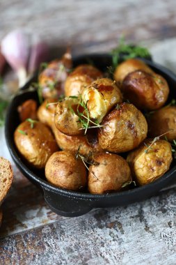 Tavadaki kırsal patates. Sarımsak ve bitkilerle kabuklu küçük patatesler..