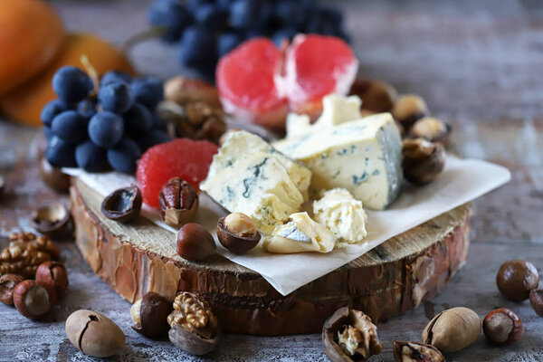 Beautiful cheese set with nuts, blue grapes and grape fruit. Keto snack. Healthy snack with wine.