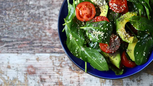 Healthy vegan salad with avocado and chia seeds. Salad with spinach, tomatoes and avocado. Salad with sesame seeds. Diet concept. Vegan food.