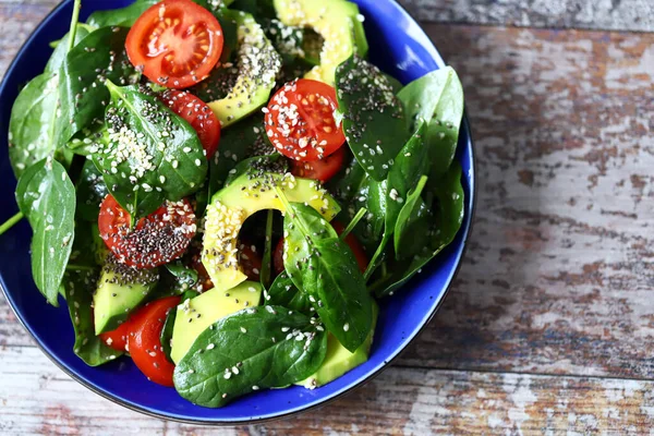 Healthy vegan salad with avocado and chia seeds. Salad with spinach, tomatoes and avocado. Salad with sesame seeds. Diet concept. Vegan food.