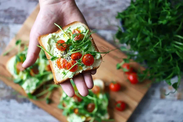Mikroyeşillikli tost. Sağlıklı bir şekilde kadeh kaldıralım. Bir adam mikroyeşillikli diyet tostu yer. Sağlıklı gıda konsepti. Süper yemek..