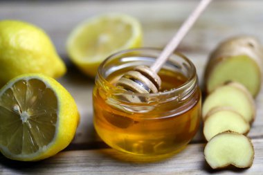 Zencefil, limon ve tahta yüzeyde bir kavanoz bal. Soğuk algınlığı için halk ilaçları. Antiviral ürünler.