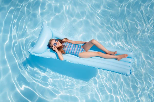 beautiful girl lies on an inflatable mattress in the pool