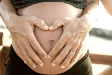 Kumsalda hamile bir kadın. Kalbinde göbek olan bir kocanın elleri..