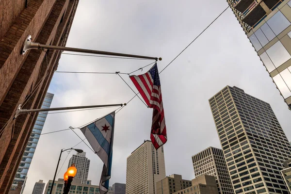 Waving flags of the city of Chicago and of the United States of America in downtown Chicago at sunset.