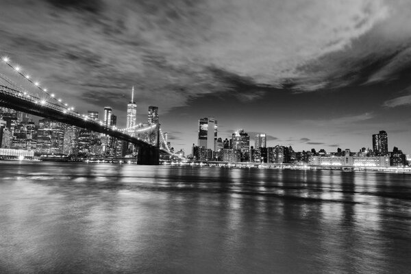 Manhattan skyline and Brooklyn Bridge by night .